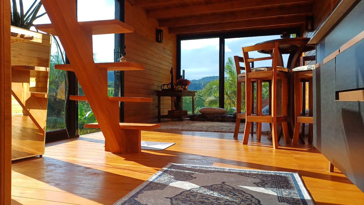 Sala de estar da cabana com janelas panorâmicas para o verde